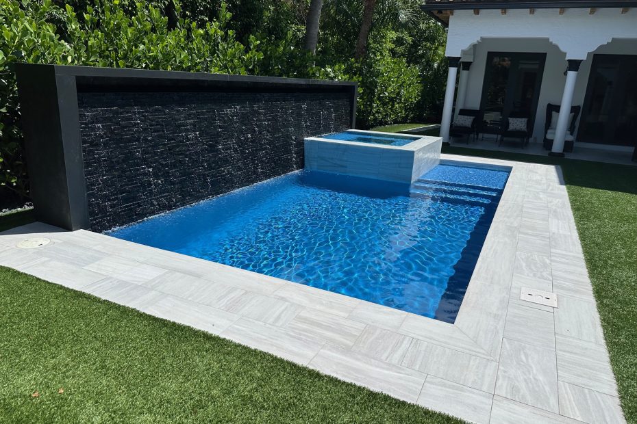 pool with waterfall and marble edging paver, built in hot tub