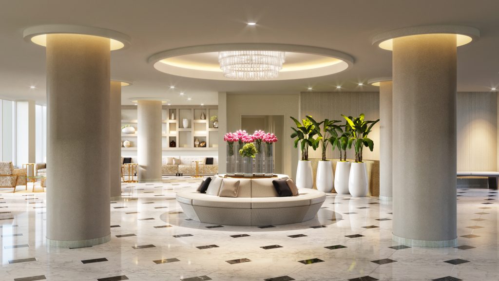 Modern condominium lounge with floor-to-ceiling windows, white curved sofas, round golden rugs, glass coffee tables, and hardwood floors overlooking tropical greenery.